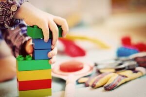 child hands stacking colorful plastic building blocks